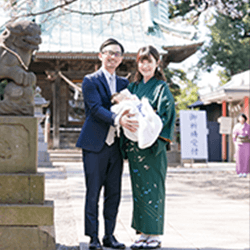 両親と赤ちゃんが神社の前で写っている