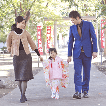 女の子と両親が手をつないで歩いている写真